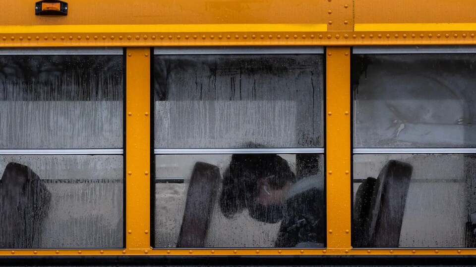 Un élève portant un masque assis dans un bus scolaire.