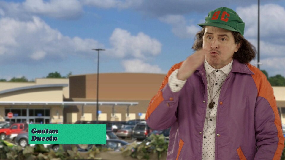 L'homme porte une casquette verte et se tient devant un stationnement.