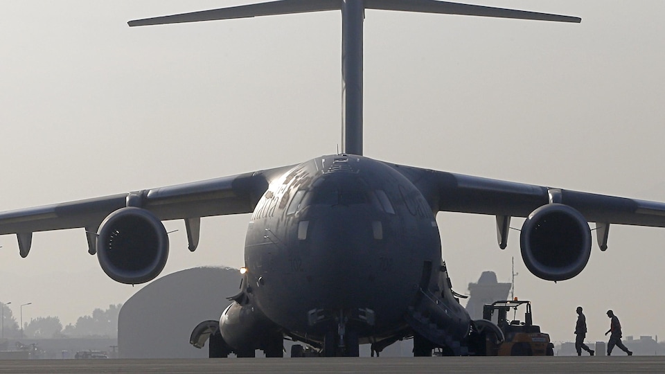 Two soldiers walking towards a plane, photographed from the front. 