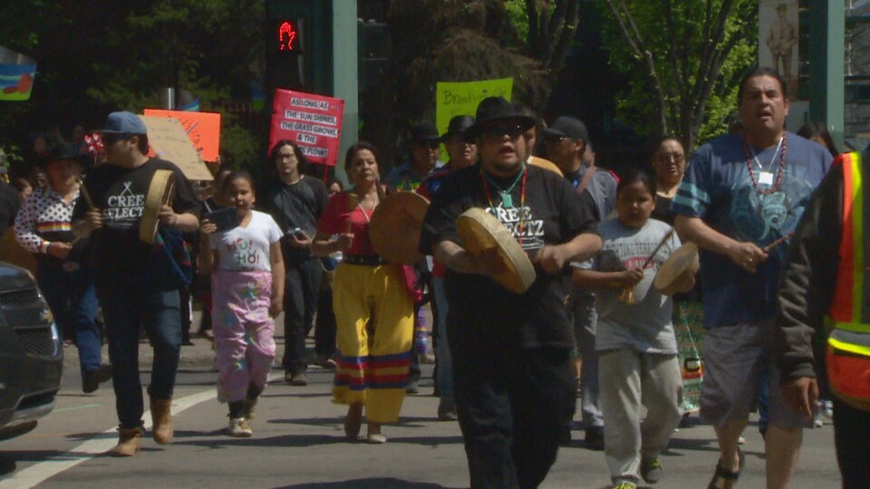 Des autochtones marchent dans le rues d'Edmonton, tambours en main.