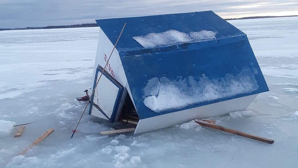 Une cabane a demi submergée dans la glace.