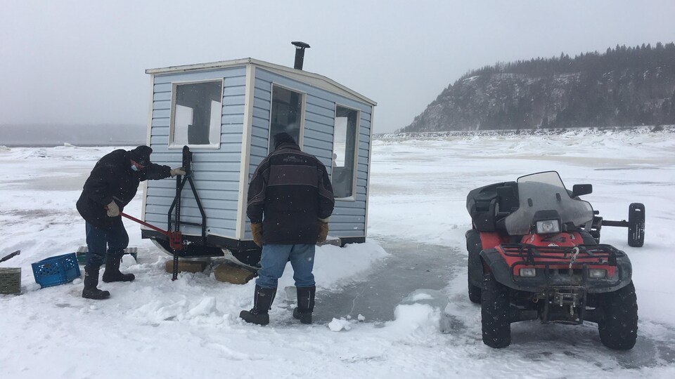 Des pêcheurs déplacent une cabane sur la glace.