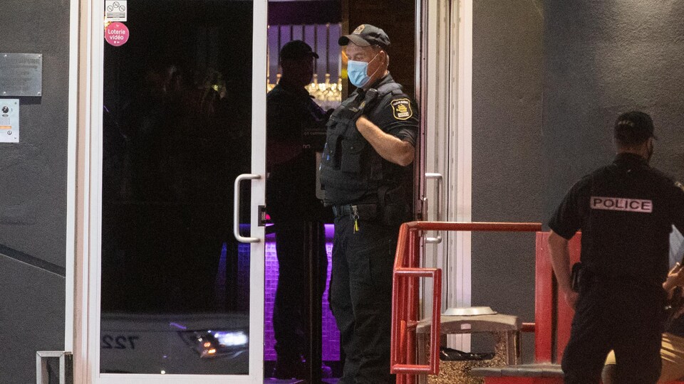 Des policiers portant le masque devant un édifice.