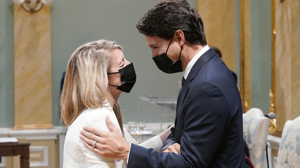 Masqués, Mélanie Joly et Justin Trudeau se regardent en souriant.