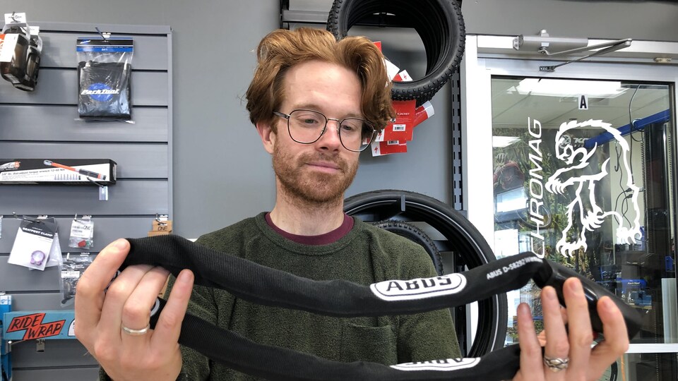 Dans un magasin de vélo, Julien Melanson exhibe un gros cadenas robuste.