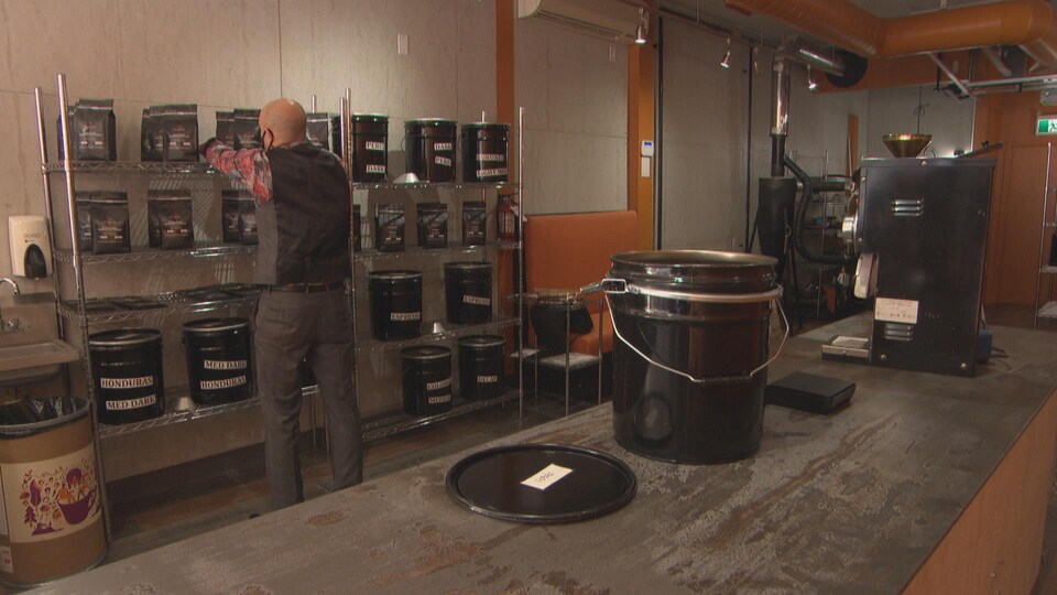 Un homme place des sacs de café sur une étagère.