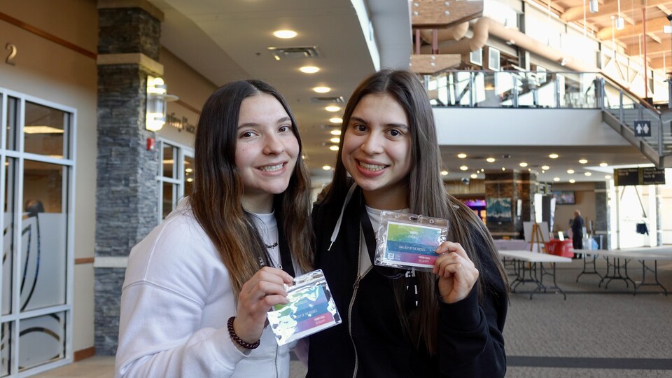 Deux filles sourient et montrent leur badge identifiant pour un forum.