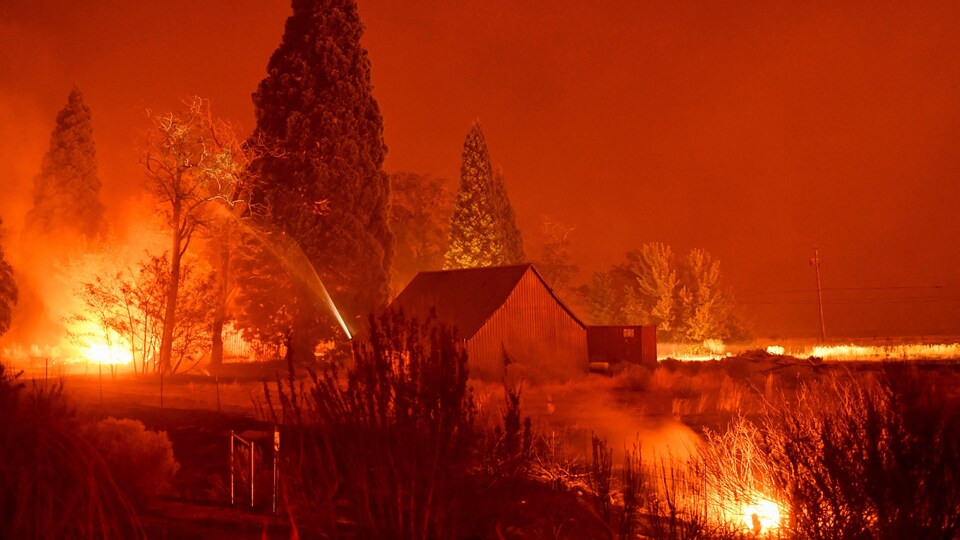 Des pompiers tentent d'éteindre les points chauds entourant une structure près de Janesville, en Californie.