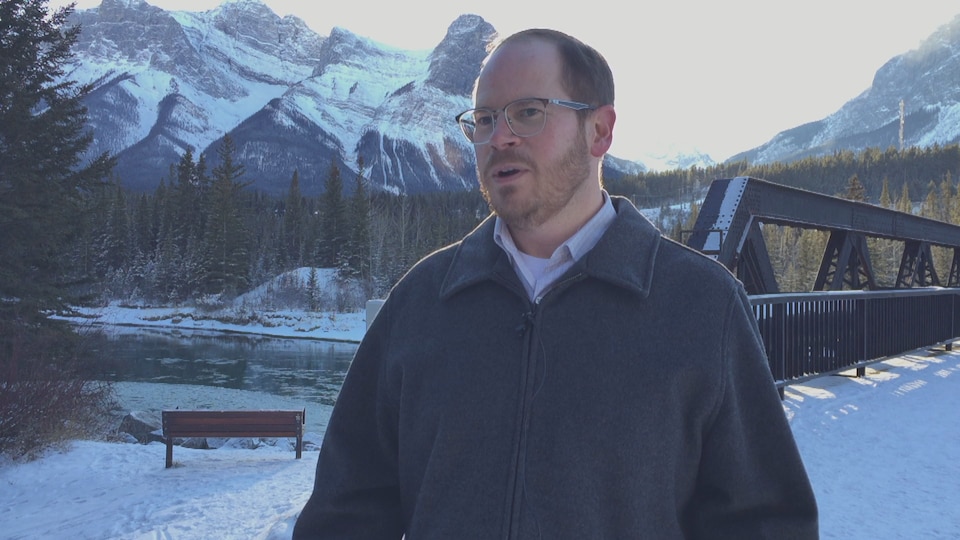 Cameron Westhead en entrevue devant le pont de Banff et les montagnes environnantes.