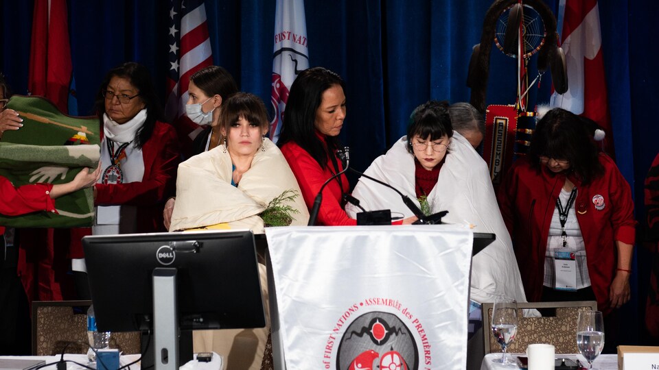 ambria Harris (gauche) et Kera Harris( droite) se font remettre une couverture, selon les valeurs des Premières Nations, lors d'une assemblée spéciale de l'Assemblée des Premières Nations à Ottawa, le 7 décembre 2022.