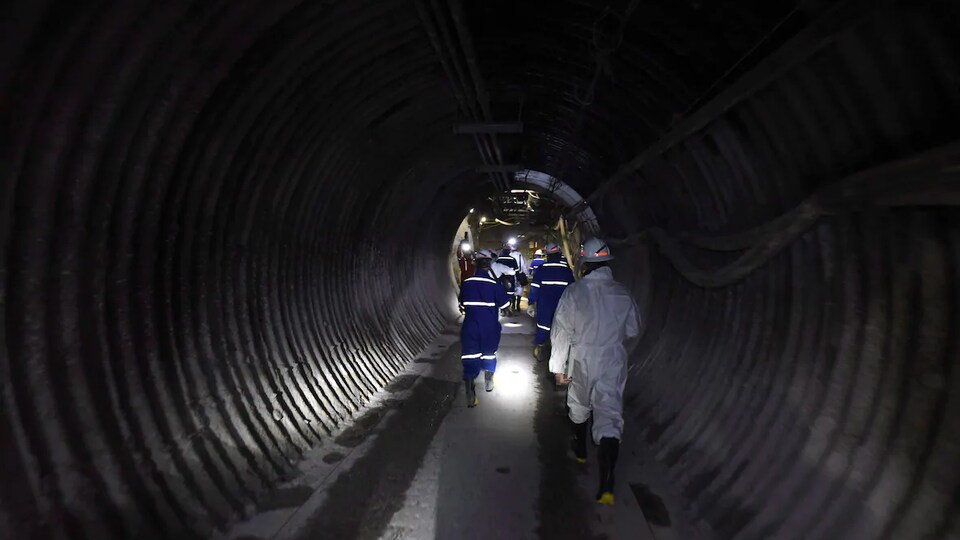 Des hommes entrent dans le tunnel d'une mine.