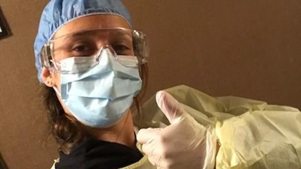 une femme en tenue d'infirmière, le pouce levé