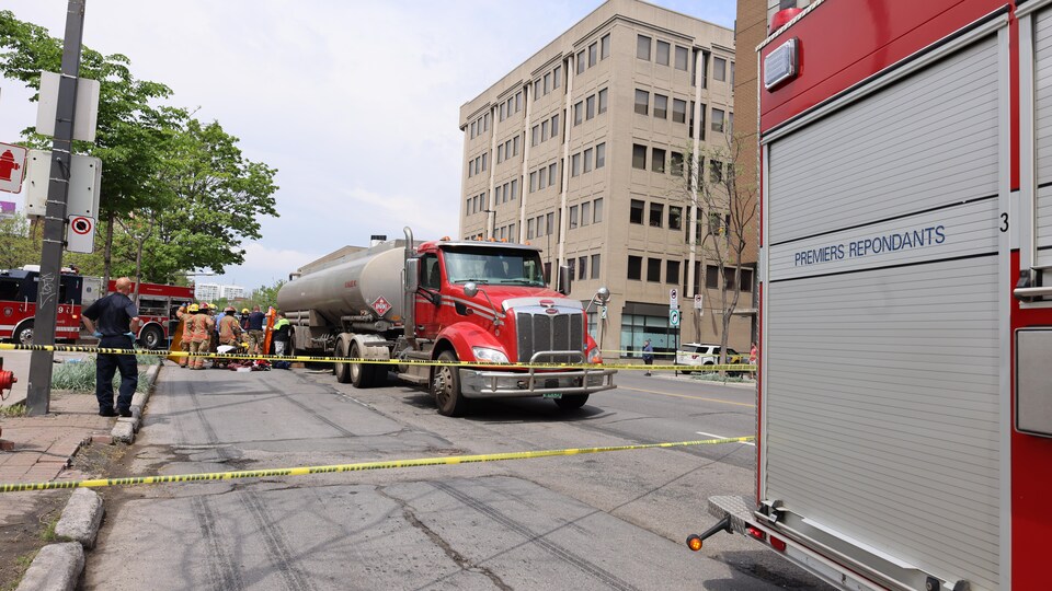 A tank truck is surrounded by yellow tape and by firefighters.