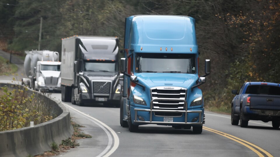 Trois camions bloqués sur une route.