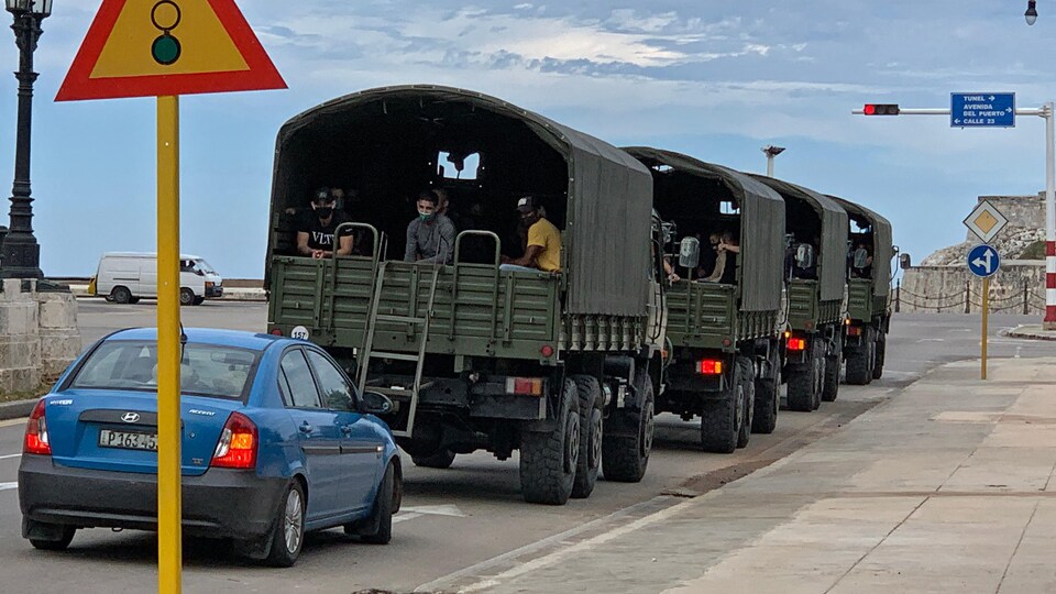 Un convoi de camions militaires roulent sur la rue.