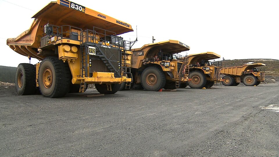 Quatre camions à benne basculante stationnés à la mine du Lac Bloom, près de Fermont.