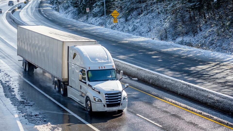 Un camion sur une autoroute en plein hiver. 