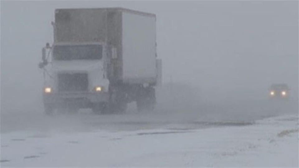 Un camion circule sur une route enneigée.