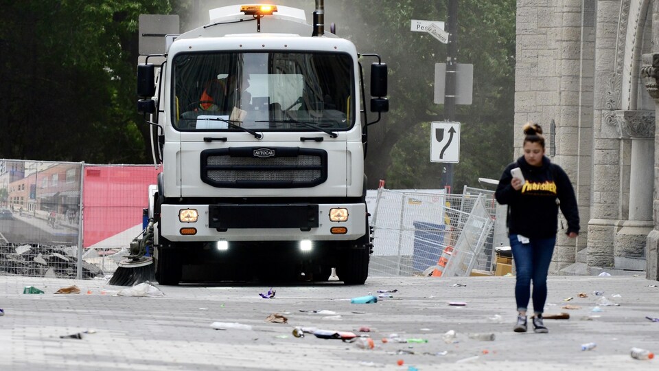 Un camion de nettoyage balaie des détritus dans une rue.