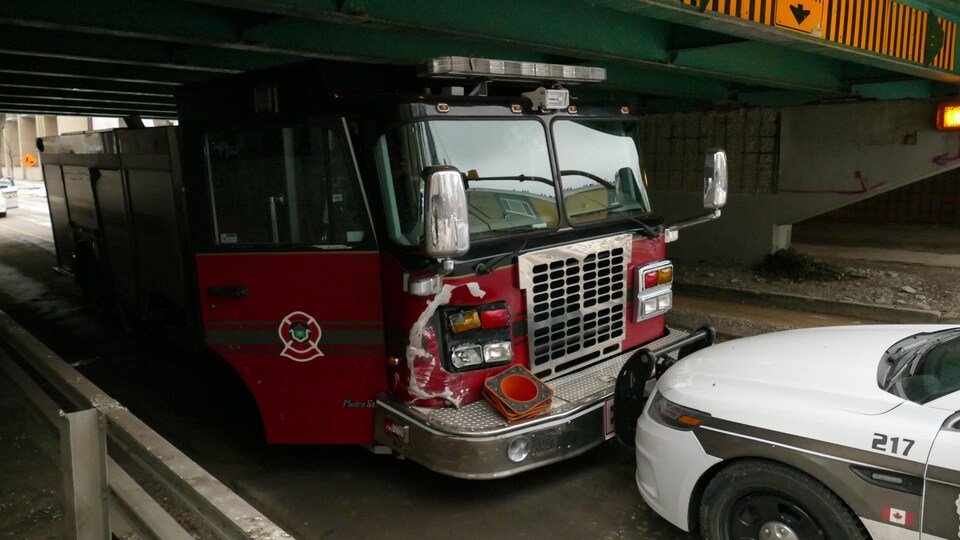 Un camion de pompier dont les phares du côté passager sont endommagés fait face à une voiture de police.