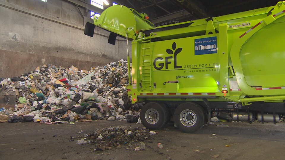 Un camion à ordures vide sa cargaison sur une montage de déchets.