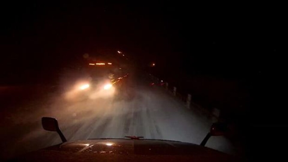 Deux camions se croisent sur une route un soir d'hiver.