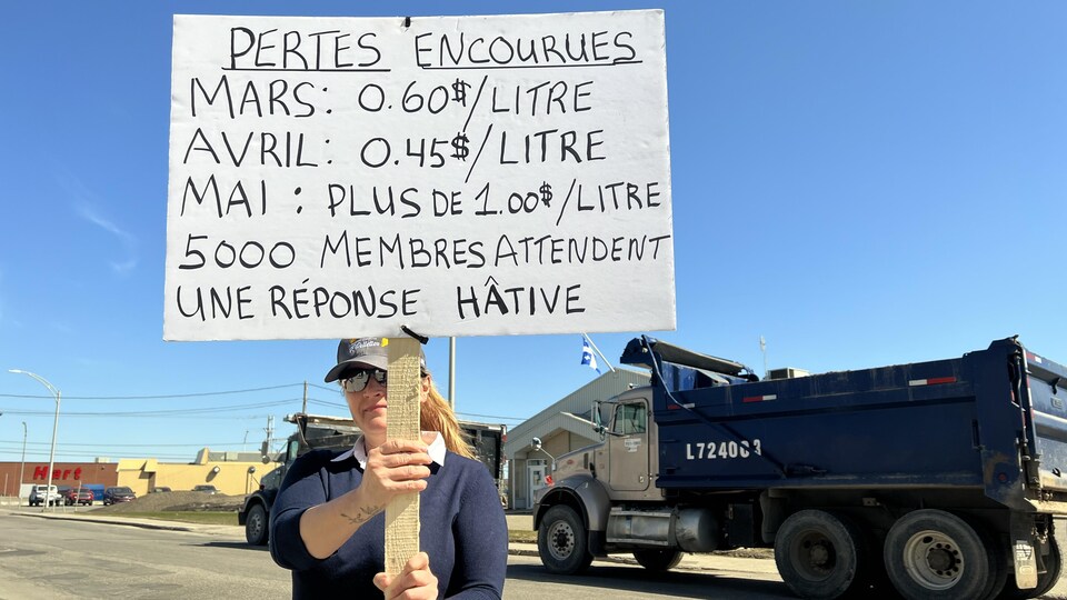 Une femme avec une pancarte devant un camion.