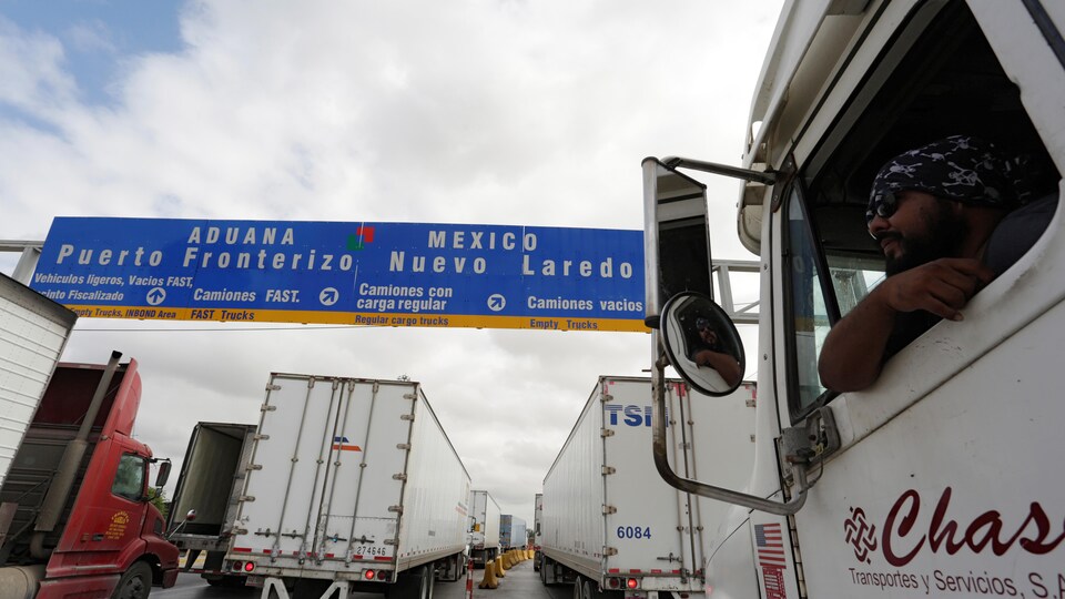 Un conducteur de camion regarde par la fenêtre au poste-frontière de Nuevo Laredo, au Mexique, où la file de camions qui attendent de passer aux États-Unis s'allonge.