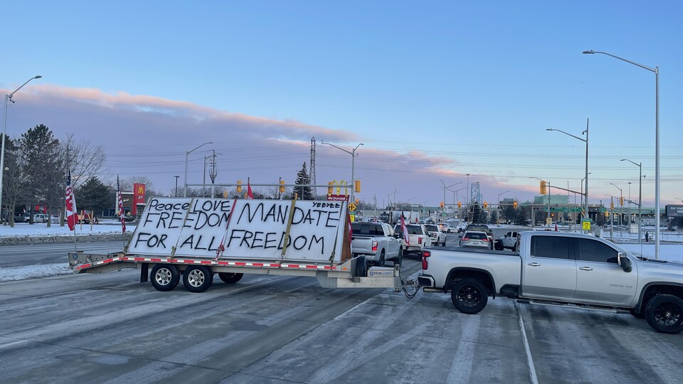 Une camionnette transportant une affiche en opposition à la vaccination obligatoire bloque la route. 