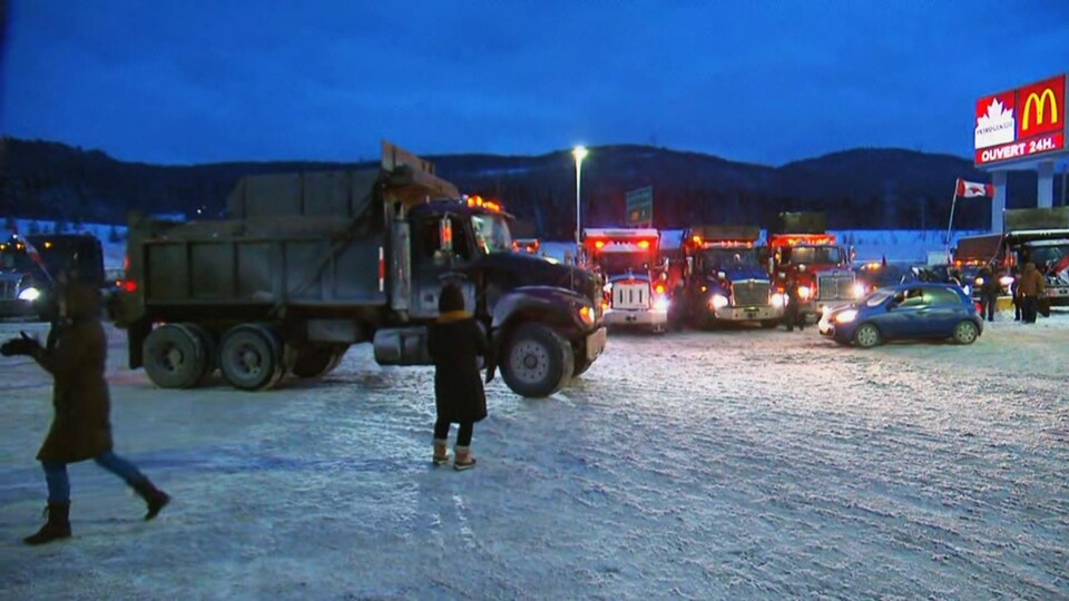 Des camions à benne dans le stationnement d'une halte routière en hiver.
