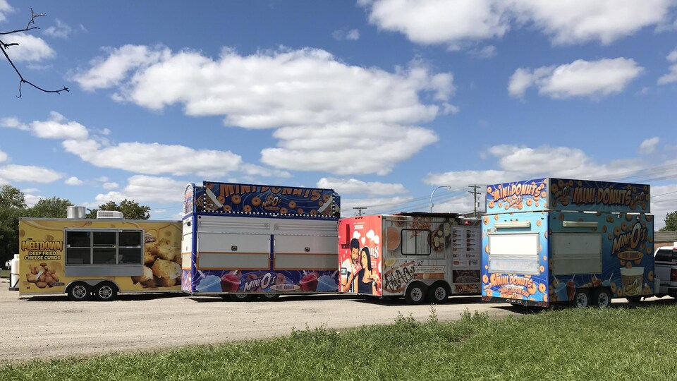 Quatre camions-restaurants sous un ciel bleu.