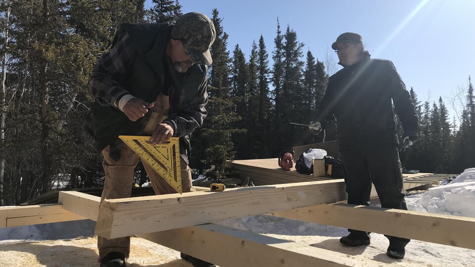 Deux travailleurs construisent la base d'une tente.