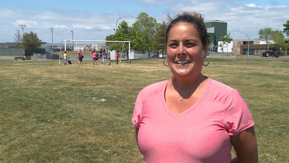 Une femme donne une entrevue sur un terrain de sport.