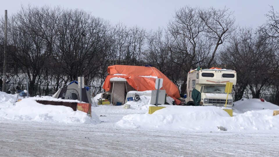 Une roulotte et un campement de fortune.