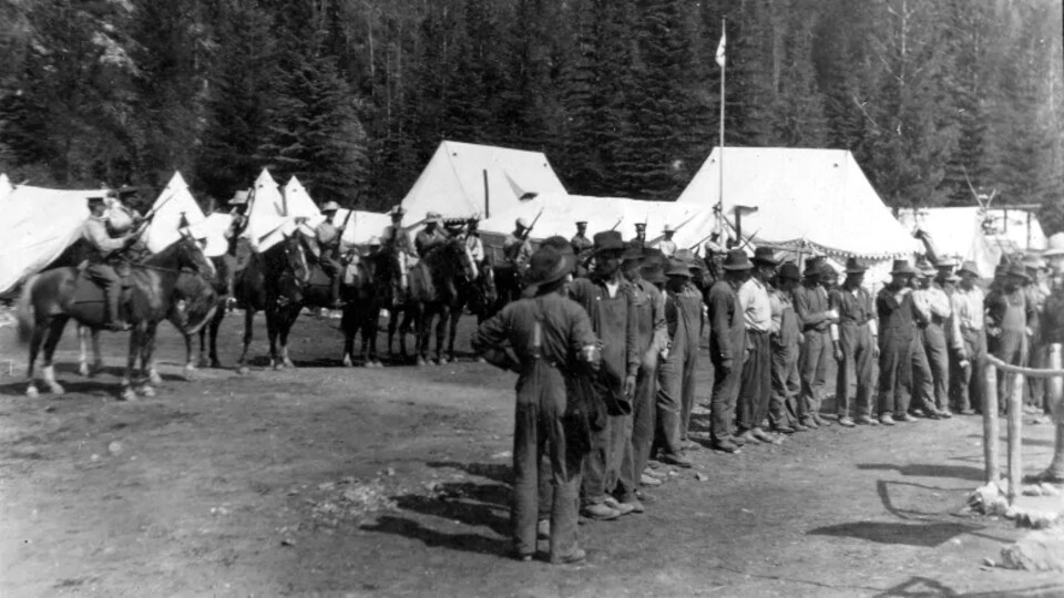 Photo d'archive d'un camp montrant des files d'hommes à pied et d'autres armés et à cheval.