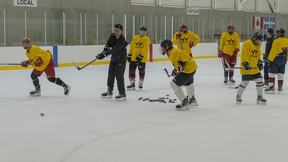 Des jeunes qui s'entraînent à jouer au hockey sur la glace, dans un aréna.