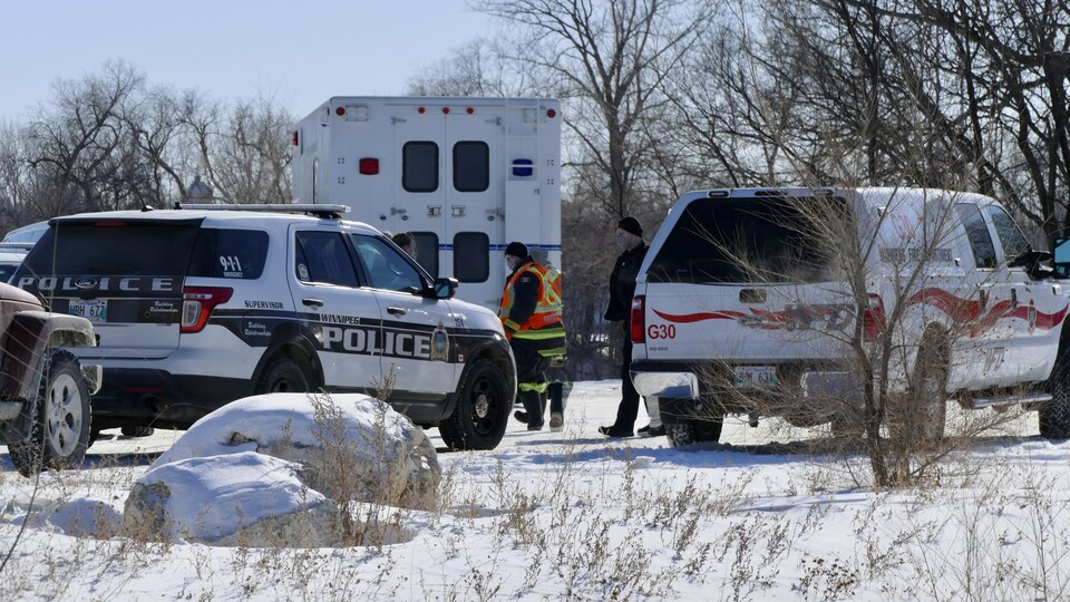 Des voitures de police et une ambulance sont stationnées dans la rue.