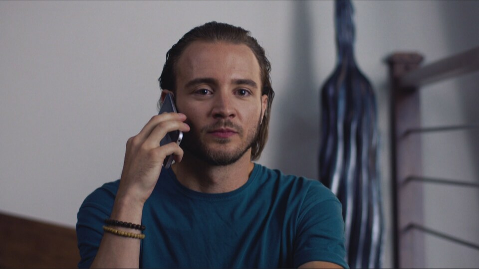 Un jeune homme tient un téléphone sur son oreille.
