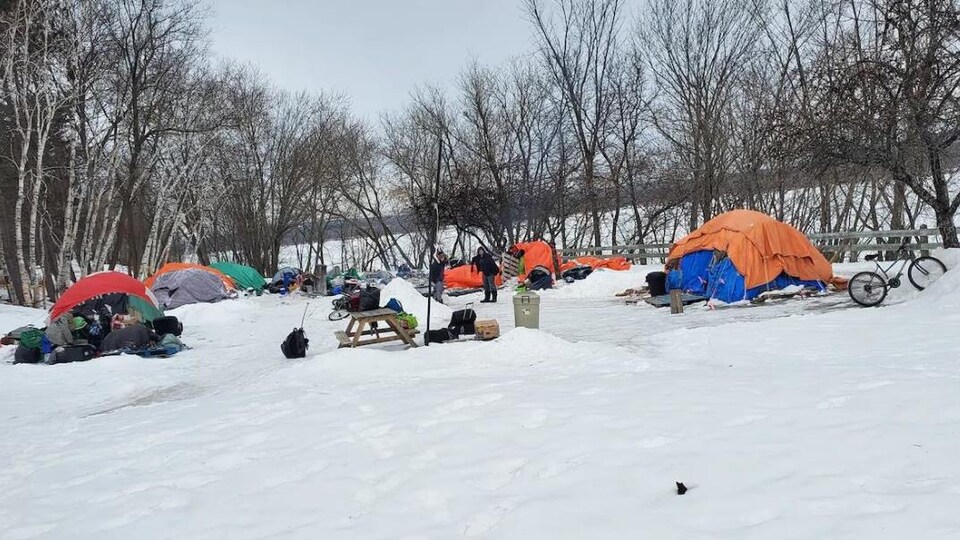Des tentes montées par des sans-abri sur un terrain enneigé. 