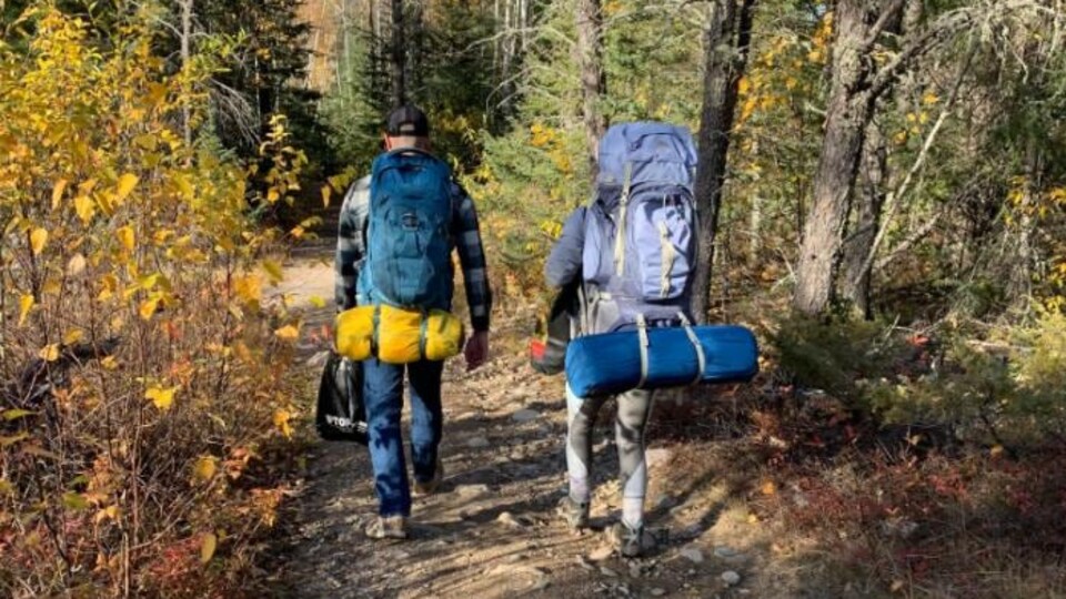 Des campeurs marchent dans un sentier avec un chien dans un parc.