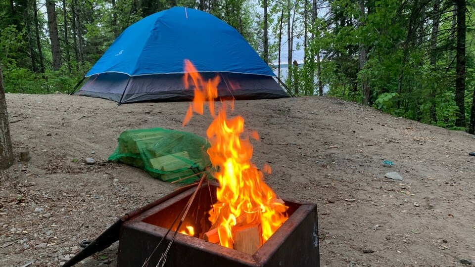 Une tente et un feu de camp sur un terrain de camping.