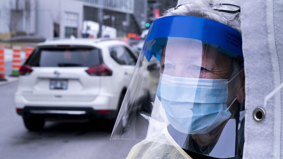 Un travailleur de la santé muni d'un masque et d'une visière.