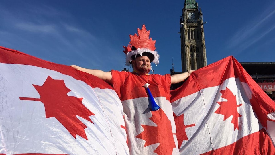 Un homme portant un costume fabriqué à partir de plusieurs drapeaux canadiens à l’occasion du 152e anniversaire de la création du pays.