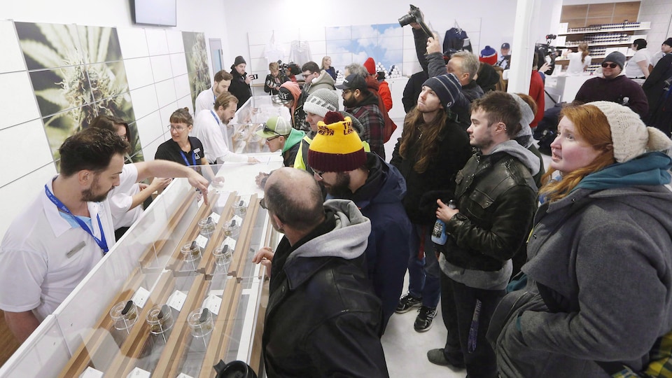 Une vingtaine de personnes devant le comptoir vitré d'un magasin de cannabis le 17 octobre 2018 à Winnipeg.