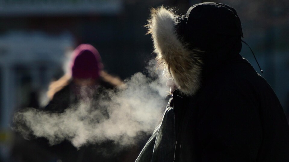 L'haleine d'une personne est blanche dans l'air froid d'hiver.
