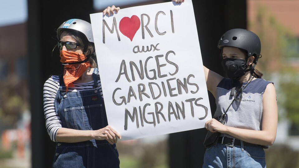 Deux femmes brandissent une pancarte lors d'une manifestation.