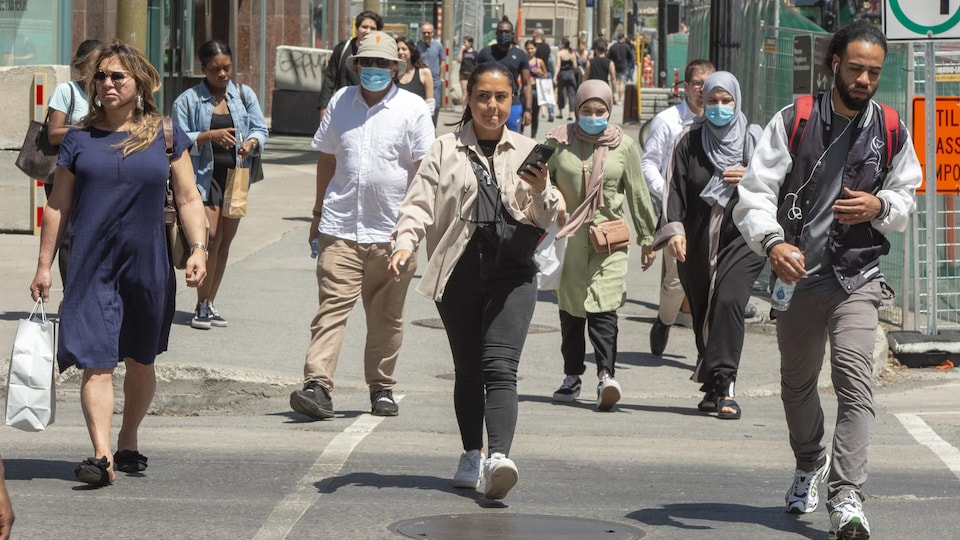 Des passants, certains portant un couvre-visage, déambulent sur la rue Sainte-Catherine à Montréal en juin 2020.