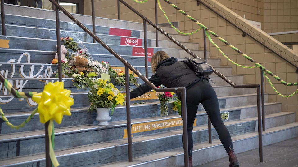Une femme dépose une gerbe de fleurs à l'aréna Elgar Petersen, où jouent les Broncos de Humboldt.