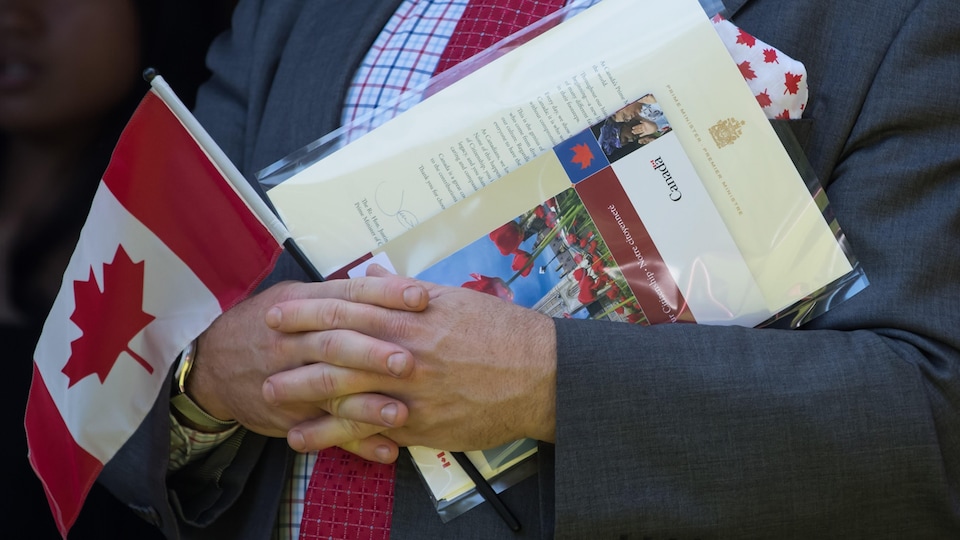 Isang tao na hawak ang Canadian flag, citizenship certificate at isang liham mula kay Prime Minister Justin Trudeau.