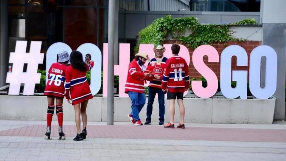 Des partisans des Canadiens de Montréal se photographient sur une place publique.